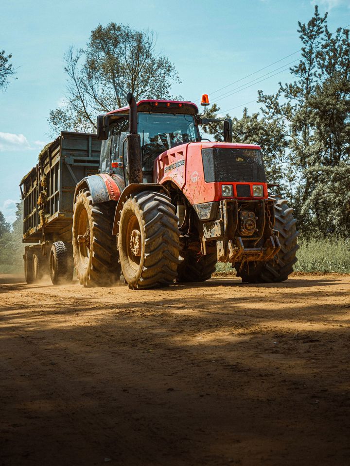 Trator puxando carreta em estrada de terra